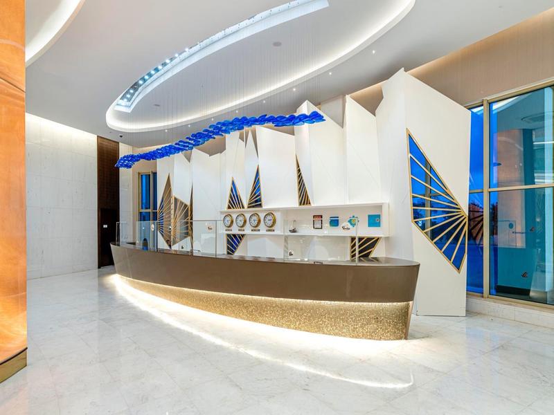 Moderne hotelreceptie met elegante gebogen balie en abstracte wanddecoratie.