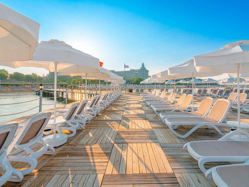 Zonnig terras met ligstoelen en parasols aan het water onder een heldere hemel