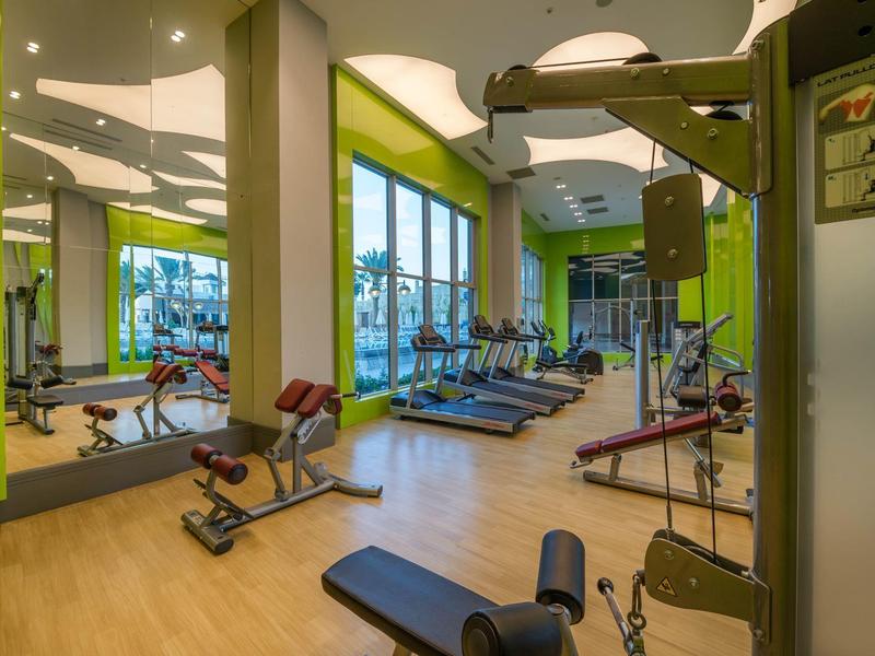 Moderne fitnessruimte met loopbanden, dumbbells en spiegelwanden in een hotel.