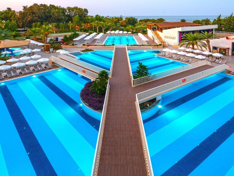 Groot modern zwembadgebied met meerdere zwembaden en ligstoelen in een hotelresort.