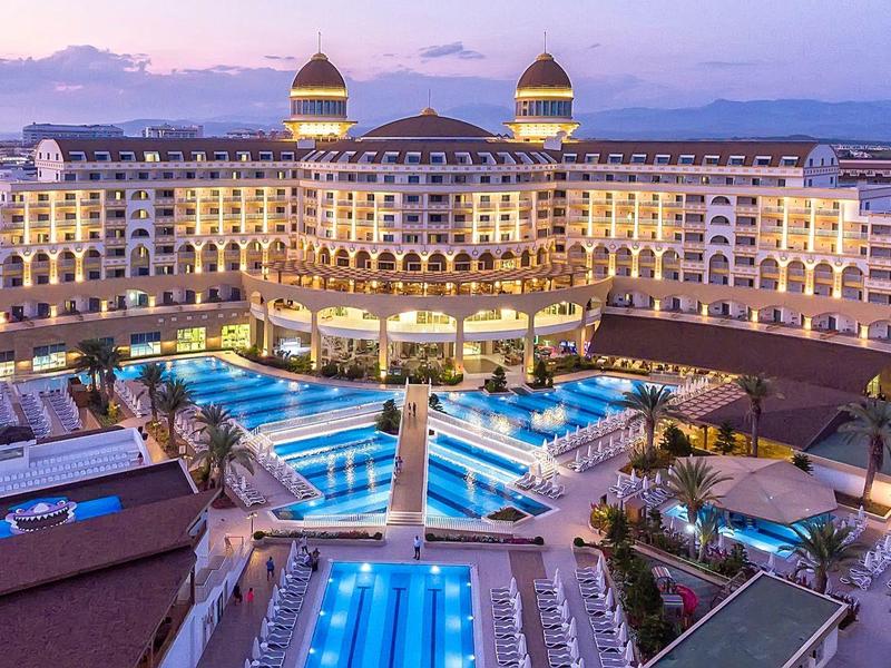 Luxe hotel bij zonsondergang met grote zwembaden en verlichte gevel