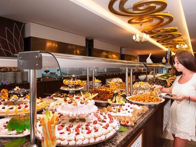 Vrouw die eten opschept bij een goed verlicht buffet in een restaurant.