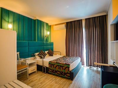 Modern hotelkamer met bed, tafel, stoel en grote ramen met gordijnen.