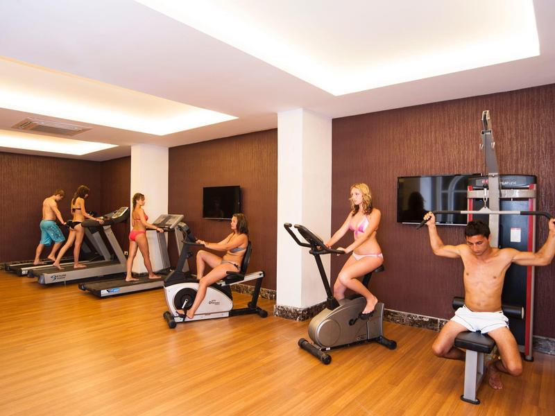 Mensen trainen in een moderne sportschool met houten vloer en fitnessapparatuur.