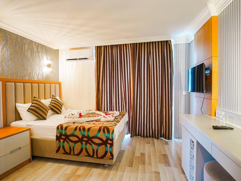 Moderne hotelkamer met tweepersoonsbed, tv, bureau en grote gordijnen.