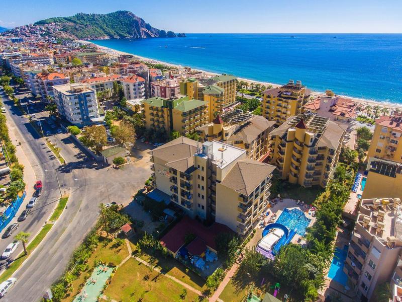 Blick auf Küstenstadt mit Mehrfamilienhäusern, Pool, Strand und blauer See im Hintergrund.