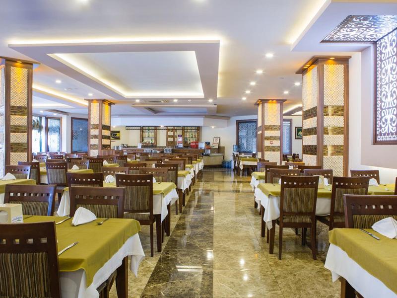 Großer, heller Speisesaal mit gedeckten Tischen, Holzstühlen und Marmorboden.