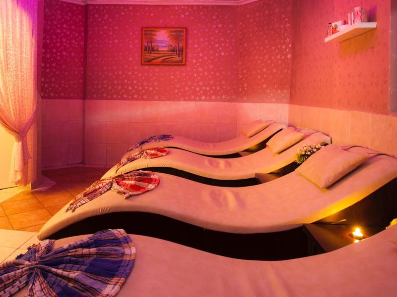 Raum mit orangener Beleuchtung, mehreren Liegen und roten Wänden, Vorhang an der Tür.