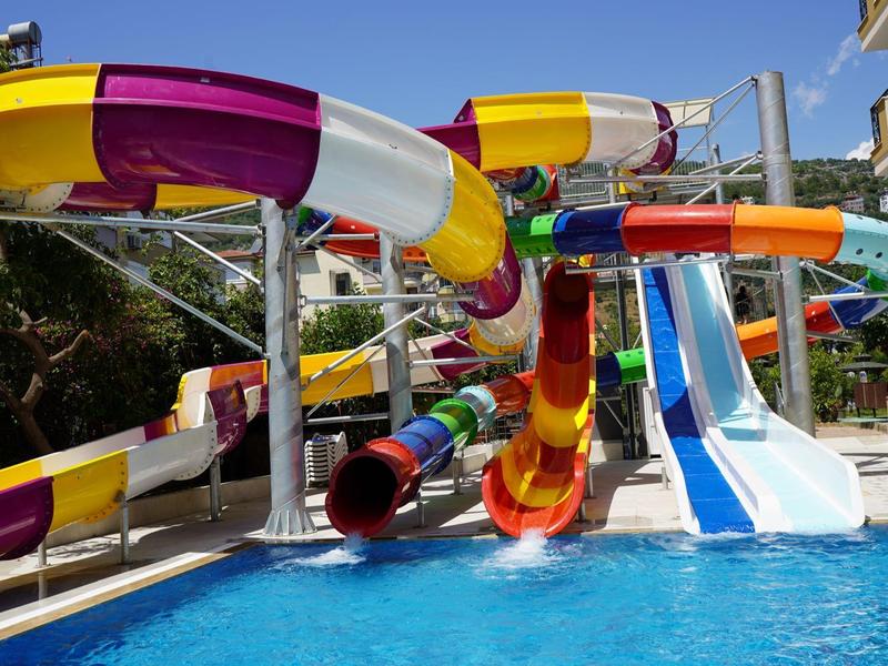 Bunte Wasserrutschen führen in ein klares Schwimmbecken unter blauem Himmel.