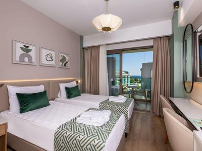 Przytulny pokój hotelowy z dwoma łóżkami pojedynczymi, balkonem i widokiem na morze.