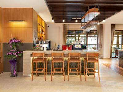 Bar d'hôtel moderne avec comptoir en bois, quatre tabourets en bois et décoration d'orchidées