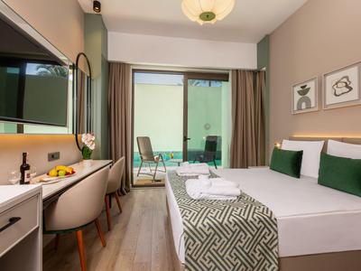 Chambre d'hôtel moderne avec lit double, bureau et balcon avec espace assis.