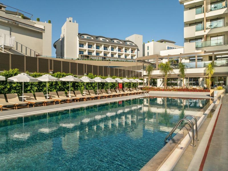 Duży hotelowy basen na zewnątrz z leżakami i parasolami pod czystym niebem.