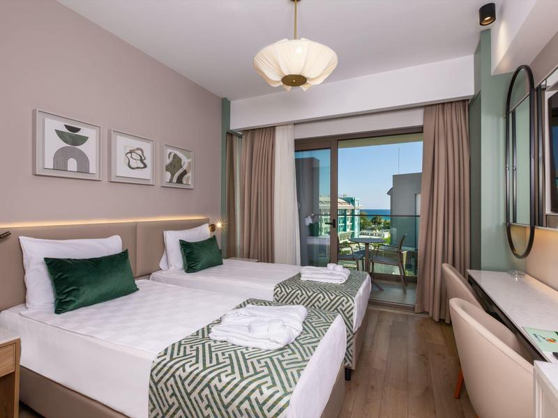 Przytulny pokój hotelowy z dwoma łóżkami pojedynczymi, balkonem i widokiem na morze.