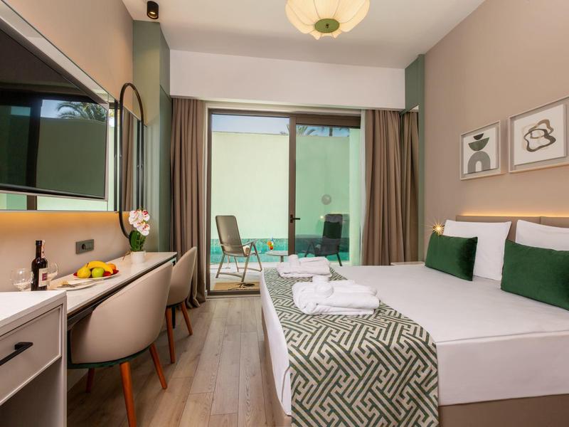 Nowoczesny pokój hotelowy z łóżkiem podwójnym, biurkiem, krzesłem i tarasem z miejscem do siedzenia.