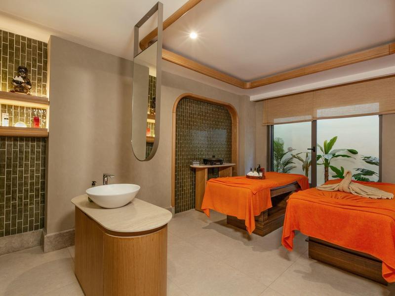 Nowoczesny pokój zabiegowy spa z dwoma łóżkami do masażu i ciepłym oświetleniem.