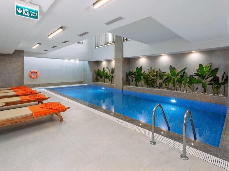 Nowoczesny basen kryty z leżakami i roślinami przy ścianie w hotelu