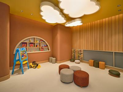 Kinderspielecke mit Teppich, kleinen Sitzsäcken, Spielzeug und warmen Holztönen in Hotelumgebung.