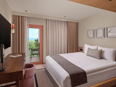 Modernes Hotelzimmer mit großem Bett, TV, Balkon und neutraler Dekoration.