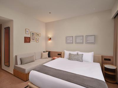 Modern eingerichtetes Hotelzimmer mit großem Bett und Sitzbereich in neutralen Farbtönen.