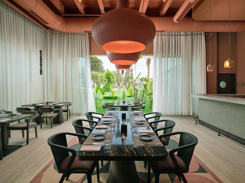 Moderner, eleganter Speiseraum mit langem Holztisch und Blick auf einen Garten.