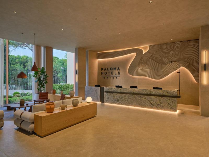 Modernes Hotellobby mit hellem Interieur, Sitzgelegenheiten und Rezeption mit Stilbeleuchtung.