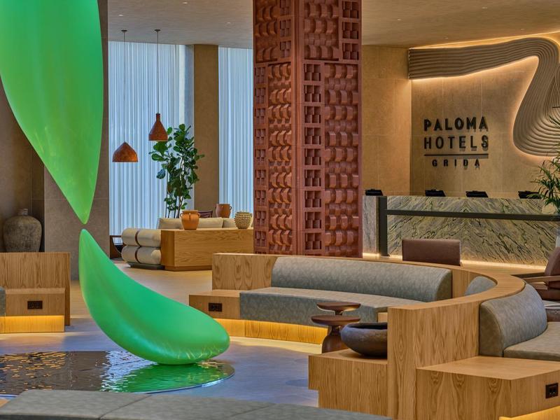 Moderner Hotel-Lobbybereich mit grüner Rutschbahn und gemütlichen Sitzmöbeln.