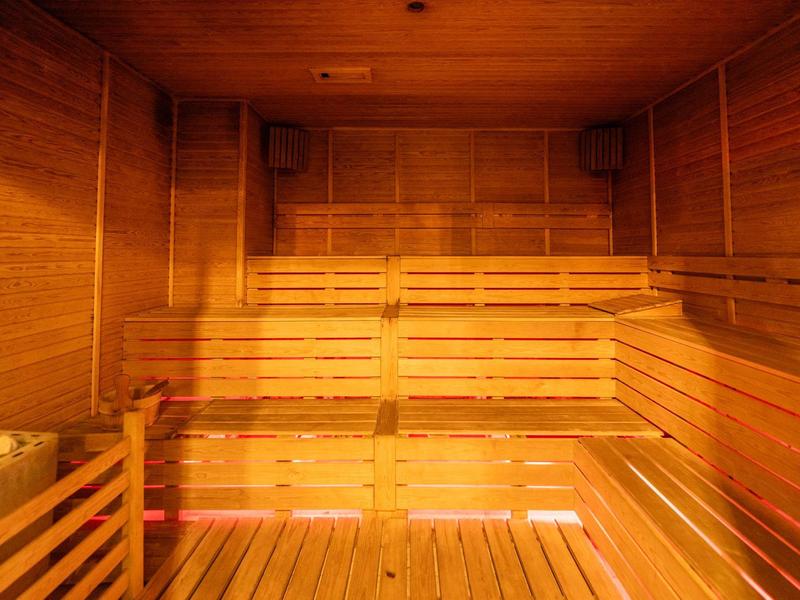 Holzsauna mit mehrstufigen Sitzbänken, Wand- und Deckenverkleidung aus Holz, warmes Licht.