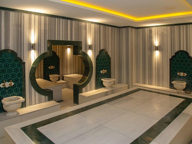 Moderner türkischer Waschraum mit Marmorbecken, verzierten Fliesen und sanfter Deckenbeleuchtung.