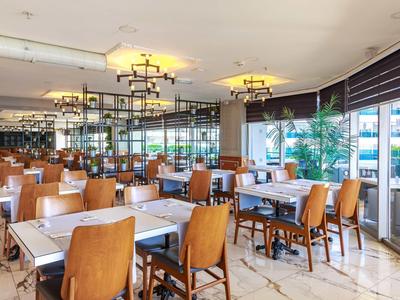 Helles modernes Restaurant mit Holztischen, braunen Lederstühlen und großen Fenstern.