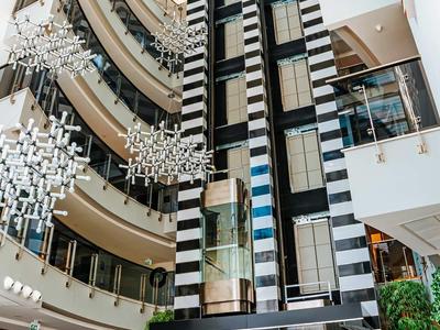 Modernes Atrium mit großem Aufzug, schwar-weißem Muster und dekorativen Hängeleuchten.