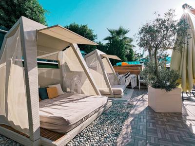 Gemütliche Outdoor-Liegemöbel mit weißen Stoffüberdachungen und Kissen auf gepflasterter Terrasse.