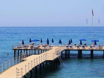 Ein langer Steg mit Sonnenschirmen und Liegestühlen ragt ins blaue Meer hinaus.