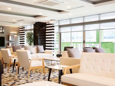 Helles, modernes Wohnzimmer mit großen Fenstern, bequemen Sesseln und eleganten Teppichen.