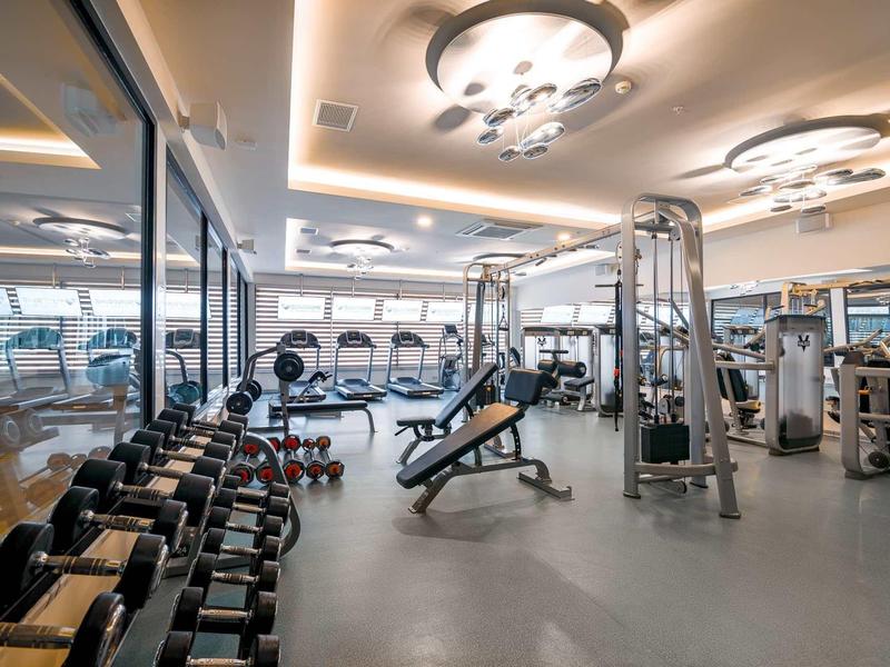 Gimnasio moderno con mancuernas, máquinas de ejercicio y espejos grandes en un hotel.