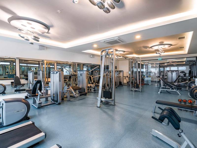 Gimnasio grande con equipos modernos y luces de techo brillantes.