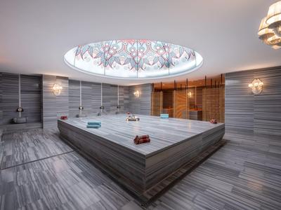 Spa moderno con gran jacuzzi revestido de mármol y ventana en el techo con diseño.
