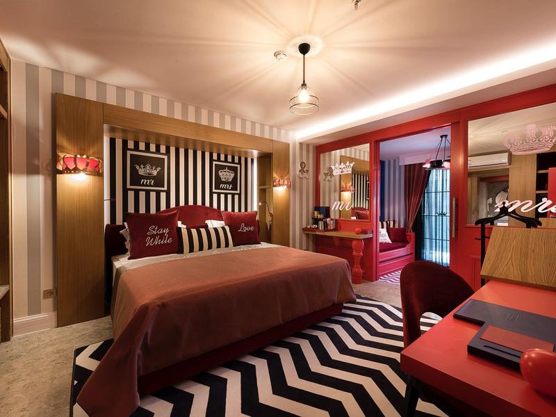 Habitación de hotel moderna con esquema de colores rojo y negro, cama doble y decoración elegante.