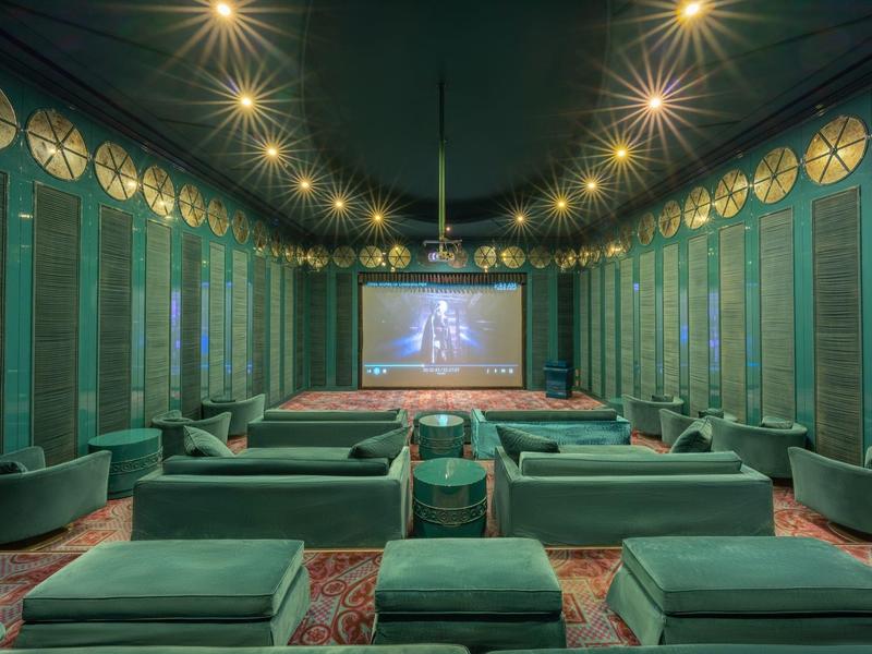 Sala de cine de lujo con asientos verdes y luces en el techo en un hotel.