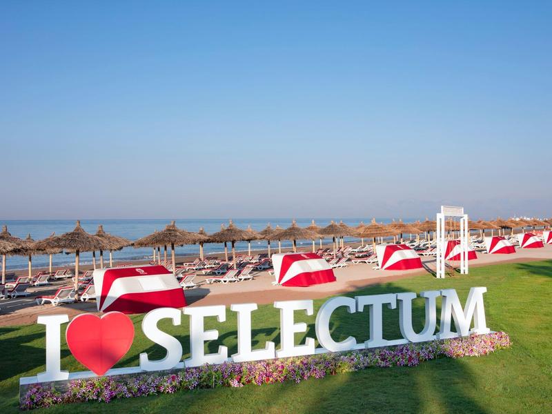 Letrero grande cerca de la playa con sombrillas y sillas, fondo de mar y cielo azul