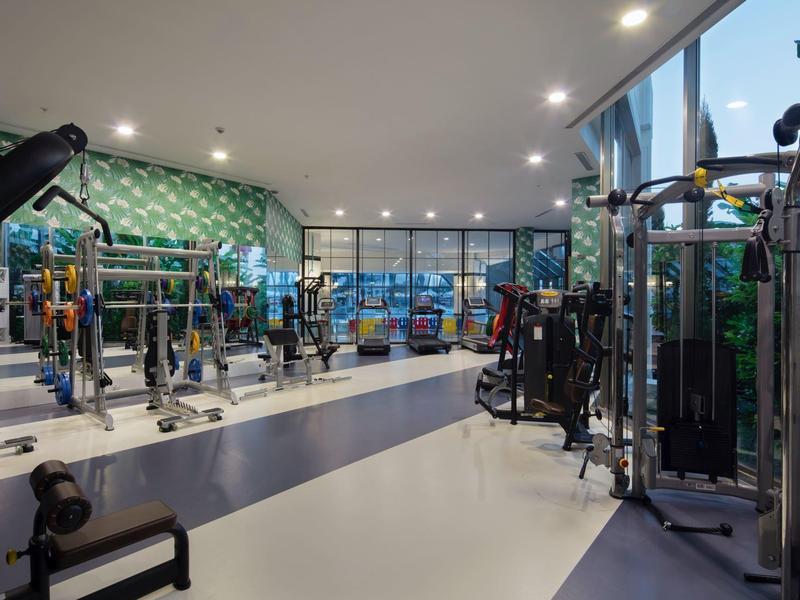 Gimnasio moderno con equipos y grandes ventanas en un hotel.