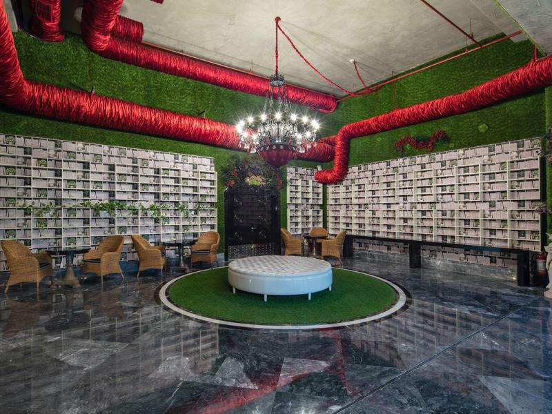 Salón moderno del hotel con pared verde, alfombra redonda y áreas de asiento elegantes.