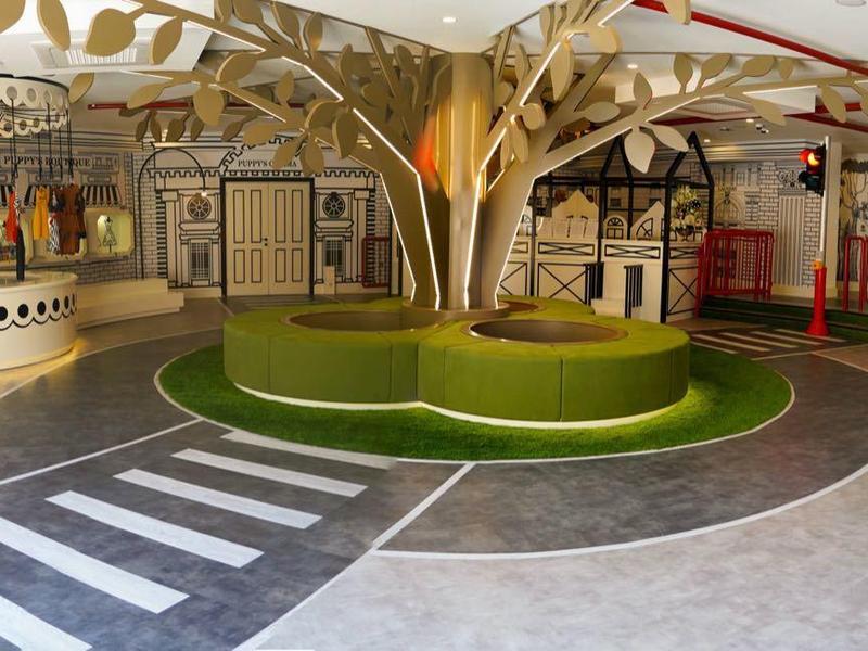 Vestíbulo moderno con banco, alfombra verde y elementos decorativos en un hotel.