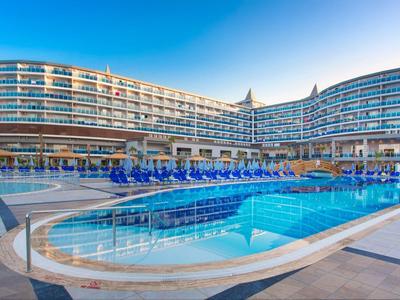 Velký moderní hotel s venkovním bazénem pod jasnou oblohou.