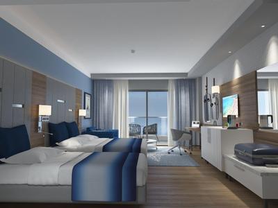 Moderní hotelový pokoj s manželskými postelemi, výhledem na moře a modrobílým zařízením.