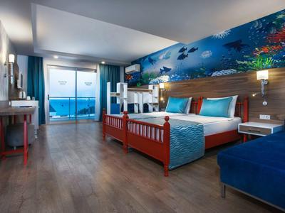 Prostorný hotelový pokoj s manželskou postelí, mořskou výzdobou a výhledem na moře.