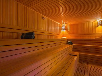 Příjemný interiér dřevěné sauny s lavicemi a tlumeným osvětlením.