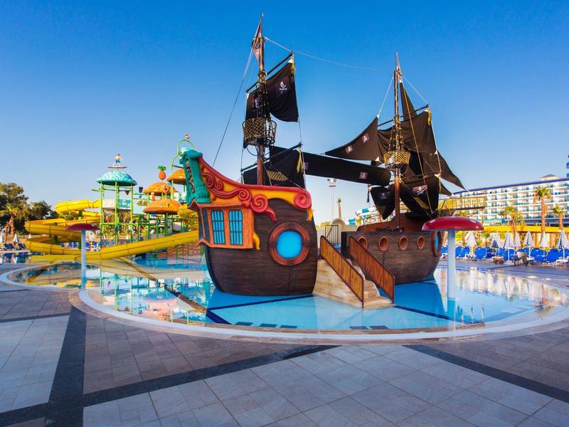 Barevný vodní pirátský dětský koutek v bazénu pod jasnou modrou oblohou.