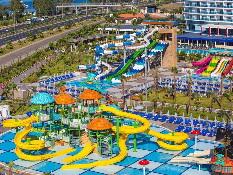 Vodní park s tobogány a atrakcemi u hotelu vedle silnice.