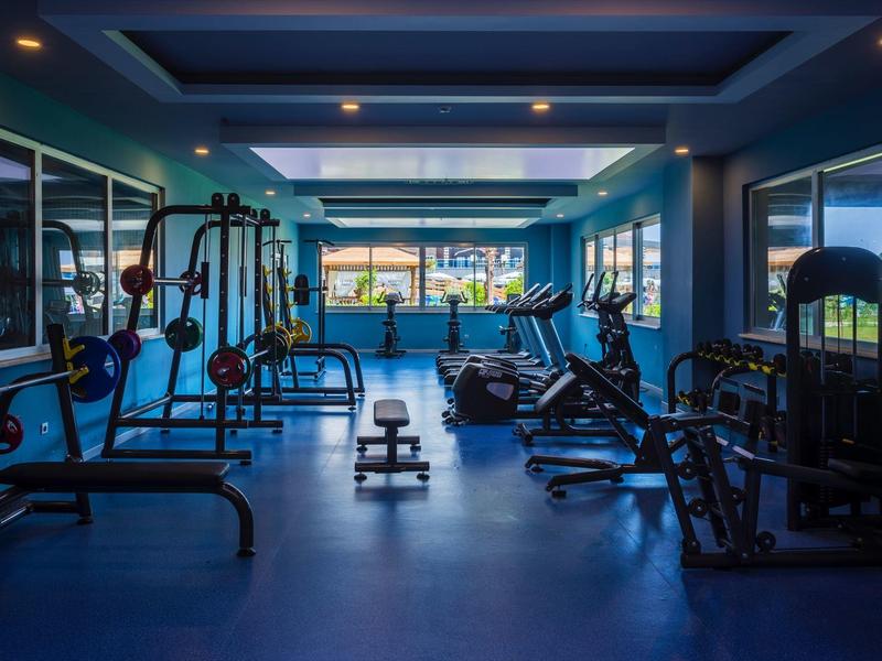 Moderní posilovna s různým vybavením a velkými okny s výhledem ven.